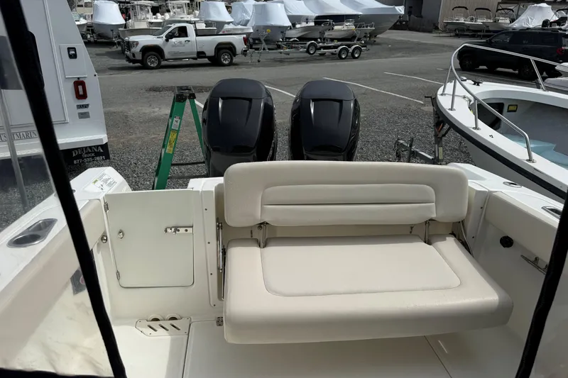 Slide: The Image of 2015 Boston Whaler 270 Vantage boat interior with seating and dual engines in a marina. - 11