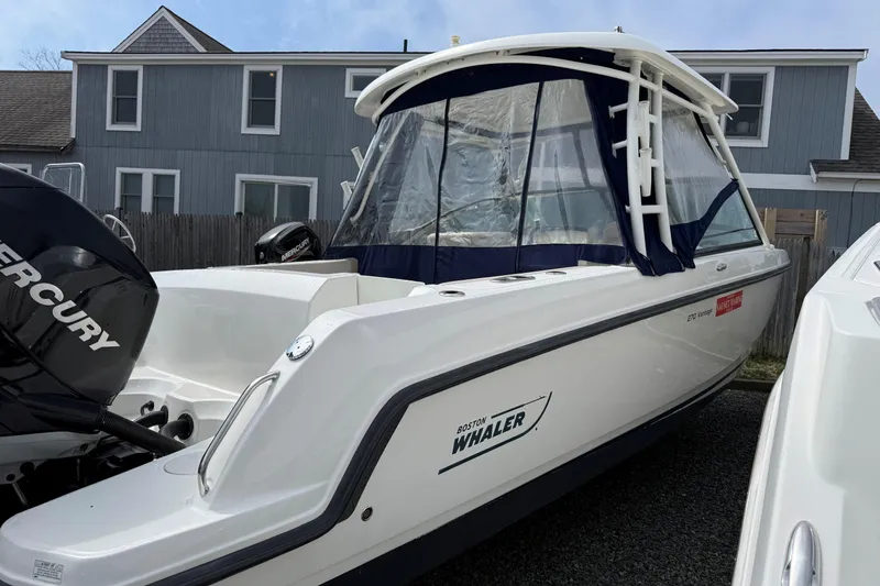 Slide: The Image of 2015 Boston Whaler 270 Vantage boat with Mercury engine, docked near a house. - 15