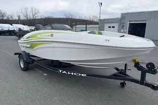 Slide: The Image of 2024 Tahoe T16 boat on trailer, white with green accents, parked outdoors. - 4