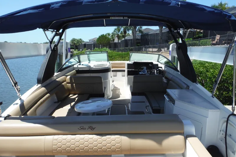 Slide: The Image of 2019 Sea Ray SDX 290 Outboard boat interior with seating and helm, docked by water. - 10