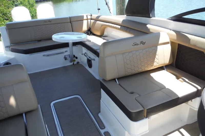 Slide: The Image of 2019 Sea Ray SDX 290 Outboard interior with beige seating and small round table. - 17
