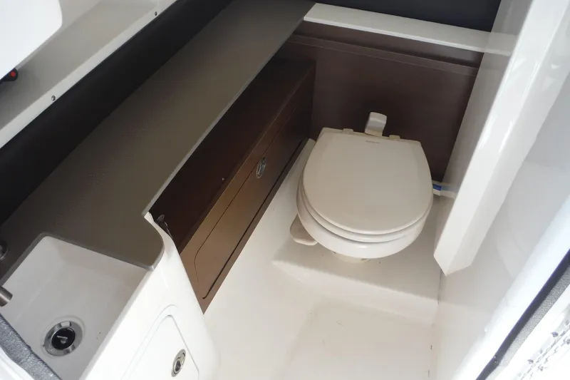 Slide: The Image of 2019 Sea Ray SDX 290 Outboard boat interior with compact marine toilet and storage. - 18
