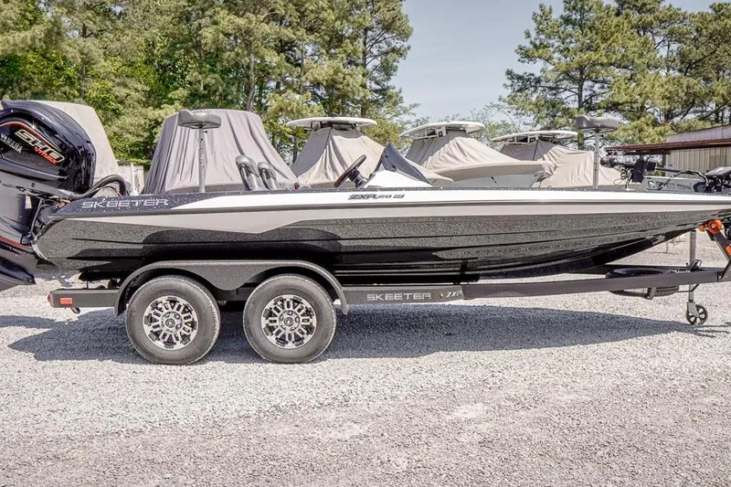 Slide: The Image of 2026 Skeeter ZXR20 SE boat on trailer, parked outdoors, surrounded by trees and covered boats. - 3