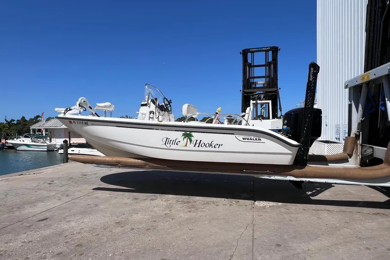 The Image of 2004 Boston Whaler 180 Dauntless boat on dock, labeled "Little Hooker," under clear blue sky. - 0