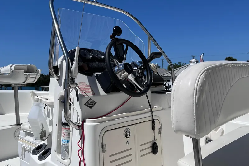 Slide: The Image of 2004 Boston Whaler 180 Dauntless boat with motor, docked under clear blue sky. - 10