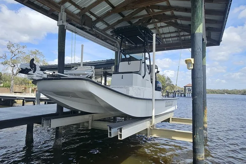 Slide: The Image of 2021 Flats Cat 21' boat on lift under dock canopy by the water. - 6