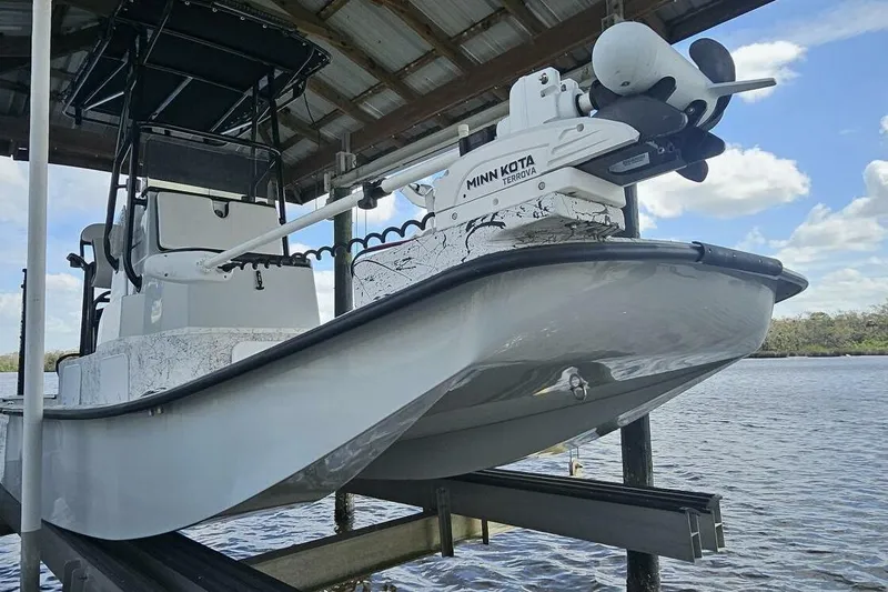 Slide: The Image of 2021 Flats Cat 21' boat with Minn Kota Terrova motor, docked under a wooden shelter. - 8