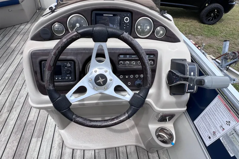 Slide: The Image of Steering console of a 2018 Berkshire 25 STS Tri Toon boat with controls and gauges. - 23