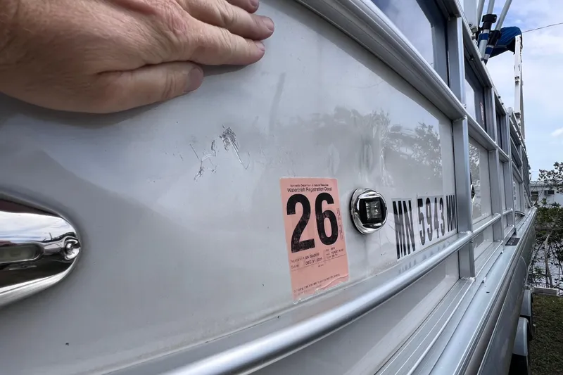 Slide: The Image of 2018 Berkshire 25 STS Tri Toon with registration sticker and visible hand. - 36
