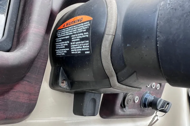 Slide: The Image of Close-up of a 2018 Berkshire 25 STS Tri Toon steering control with warning label. - 40