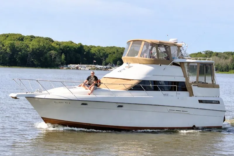 The Image of 1991 Silverton 41 Motor Yacht cruising on a serene lake with lush green shoreline. - 52