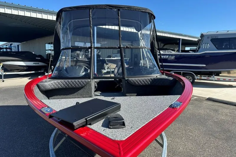 Slide: The Image of 2026 Starweld 17 SXT boat with red trim and windshield, parked outdoors. - 2