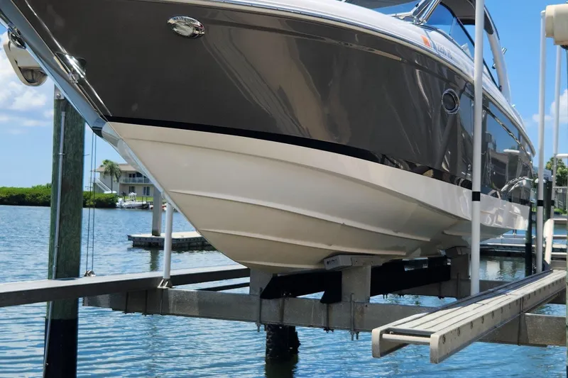 Slide: The Image of 2010 Regal 2700 ES Bowrider on a boat lift by the water. - 2
