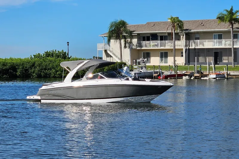 Slide: The Image of 2010 Regal 2700 ES Bowrider cruising on a sunny waterfront near a residential area. - 48