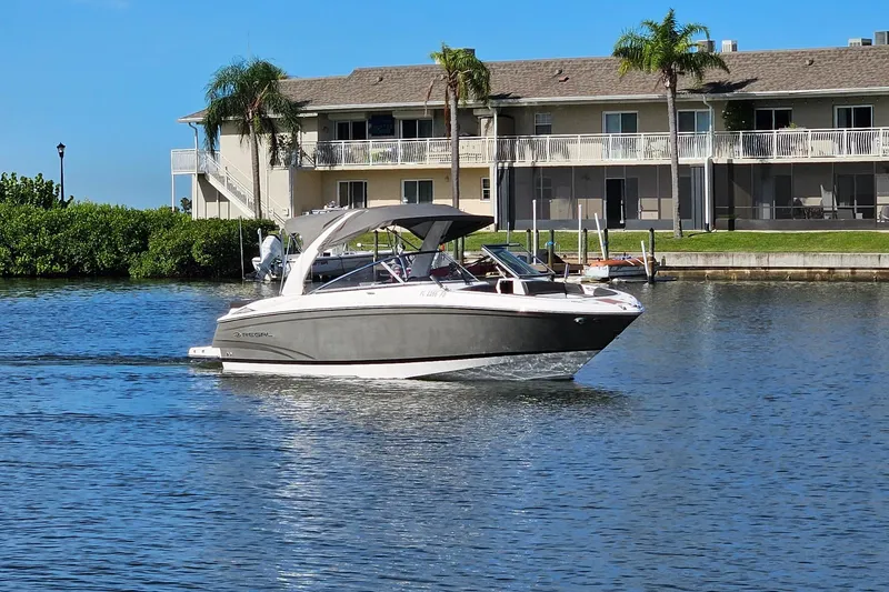 Slide: The Image of 2010 Regal 2700 ES Bowrider cruising on a sunny waterfront near residential buildings. - 49