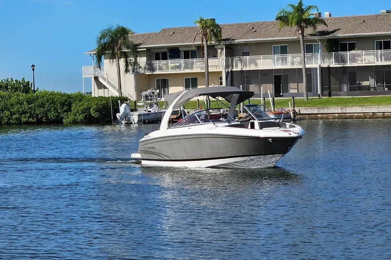 Slide: The Image of 2010 Regal 2700 ES Bowrider cruising on a sunny waterfront near residential buildings. - 50