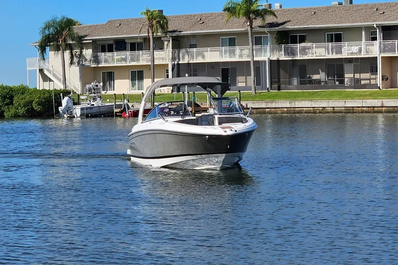 Slide: The Image of 2010 Regal 2700 ES Bowrider cruising on a sunny waterfront near residential buildings. - 51