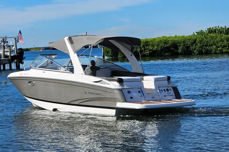 Slide: The Image of 2010 Regal 2700 ES Bowrider cruising on a sunny day, featuring sleek design and canopy. - 59