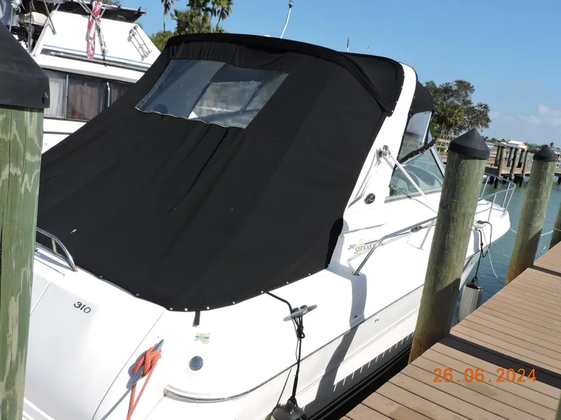 Slide: The Image of 2002 Sea Ray 310 Sundancer docked with black cover, sunny day. - 2