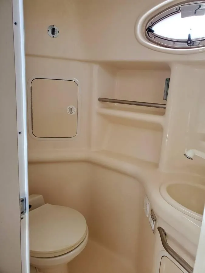 Slide: The Image of 2002 Sea Ray 310 Sundancer bathroom with toilet, sink, and storage compartments. - 43