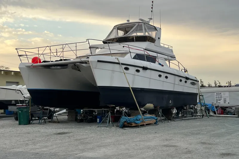 Slide: The Image of 2009 Africat Marine 420 catamaran on dry dock, under a cloudy sky. - 10