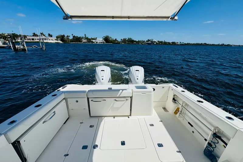 Slide: The Image of 2021 Pursuit OS 355 Offshore boat on open water, showcasing spacious deck and twin engines. - 13