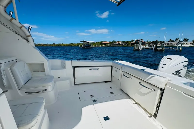 Slide: The Image of 2021 Pursuit OS 355 Offshore boat interior with seating, storage, and Yamaha engine on a sunny day. - 19