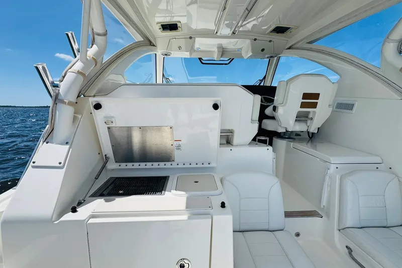 Slide: The Image of 2021 Pursuit OS 355 Offshore boat interior with seating and helm, on a sunny day. - 23