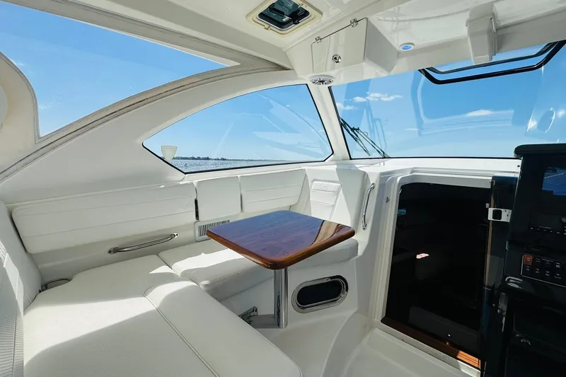 Slide: The Image of Interior of 2021 Pursuit OS 355 Offshore boat with white seating and wooden table. - 26