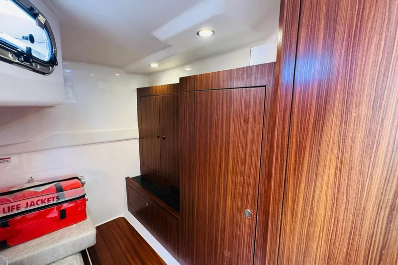 Slide: The Image of 2021 Pursuit OS 355 Offshore cabin interior with wood paneling and life jackets. - 43