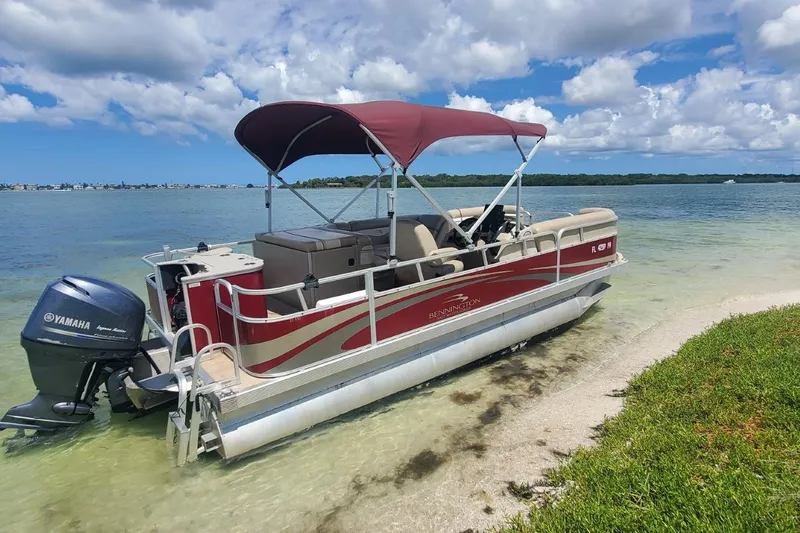 Slide: The Image of 2012 Bennington 22 SSI pontoon boat with Yamaha motor on a sandy shore. - 2