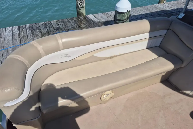 Slide: The Image of 2012 Bennington 22 SSI boat interior with beige seating by a dock. - 6