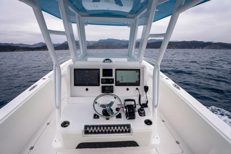 Slide: The Image of 2024 Invincible 33 Catamaran helm with navigation screens, steering wheel, and ocean view. - 17