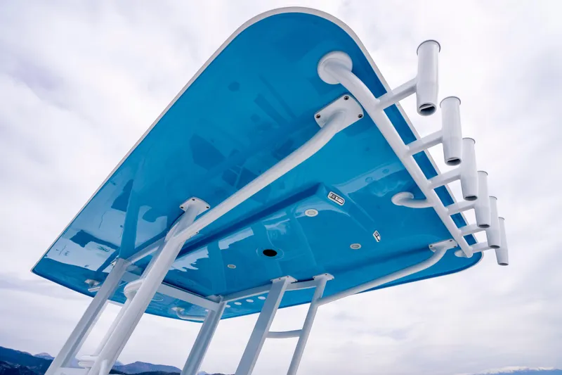 Slide: The Image of 2024 Invincible 33 Catamaran's blue T-top with rod holders against cloudy sky. - 23