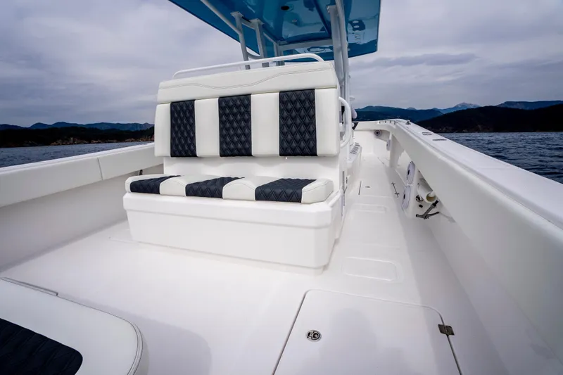 Slide: The Image of 2024 Invincible 33 Catamaran with sleek seating, cruising on open water under cloudy skies. - 25