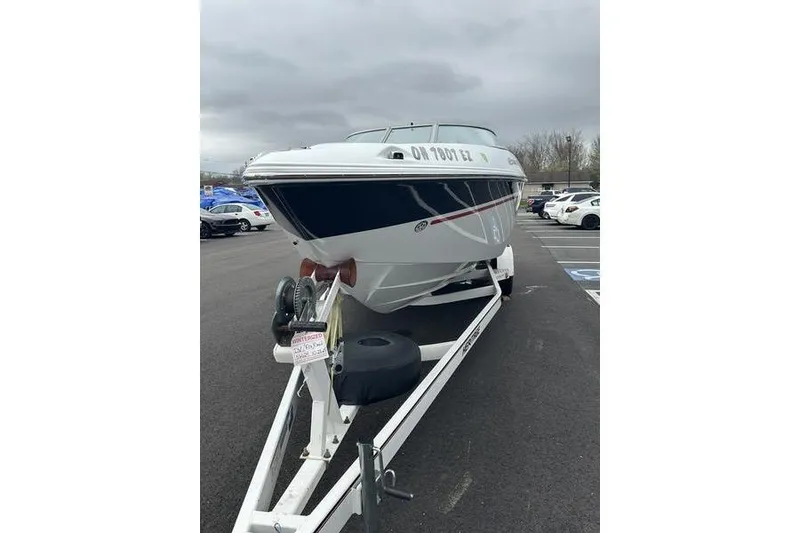 Slide: The Image of 2006 Custom 245 Boss boat on trailer in parking lot, overcast sky. - 13