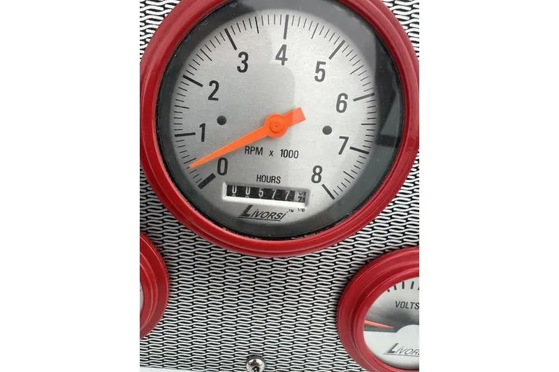 Slide: The Image of Tachometer gauge with red trim on a 2006 Custom 245 Boss boat dashboard. - 3