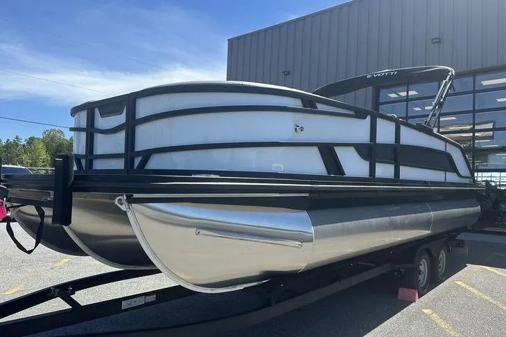 The Image of 2026 Evotti 523QL pontoon boat on trailer outside a modern building. - 1