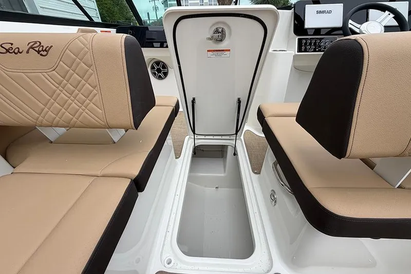 Slide: The Image of 2026 Sea Ray SDX 270 Outboard interior with open storage compartment and beige seating. - 19