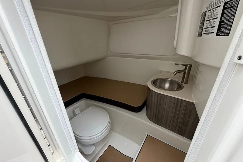 Slide: The Image of Interior of 2026 Sea Ray SDX 270 Outboard boat, featuring a compact bathroom with toilet and sink. - 25