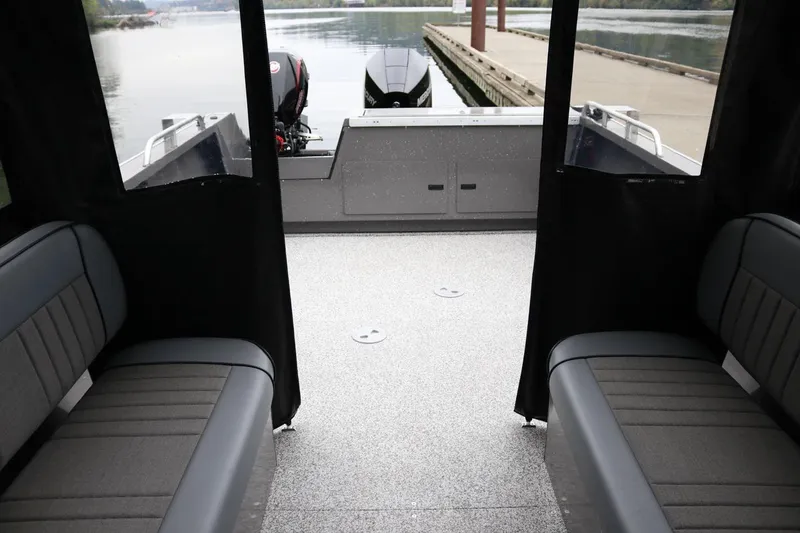 Slide: The Image of 2026 Alumaweld Intruder 22 boat interior with seating, docked by calm waters. - 12