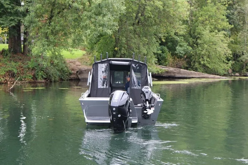 Slide: The Image of 2026 Alumaweld Intruder 22 boat navigating a serene, tree-lined waterway. - 29