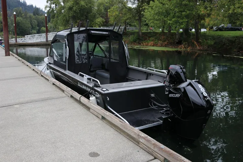 Slide: The Image of 2026 Alumaweld Intruder 22 boat docked on a serene lake with lush greenery. - 30