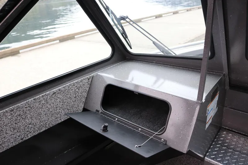Slide: The Image of 2026 Alumaweld Intruder 22 boat interior with open storage compartment and window view. - 7