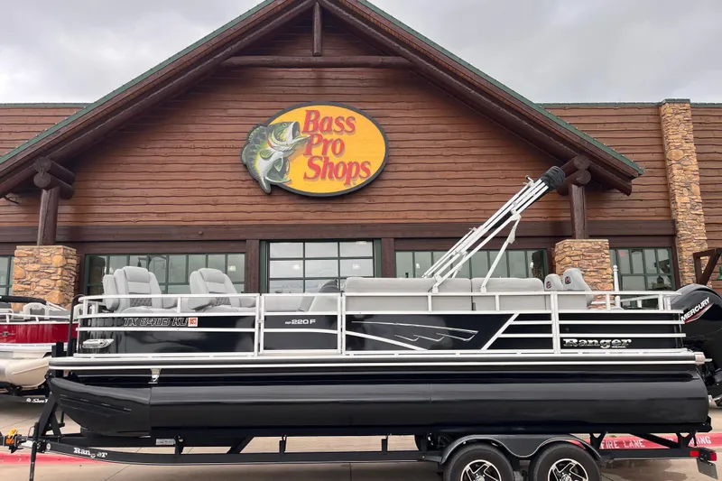 The Image of 2024 Ranger Reata 220FC boat displayed outside Bass Pro Shops store. - 0