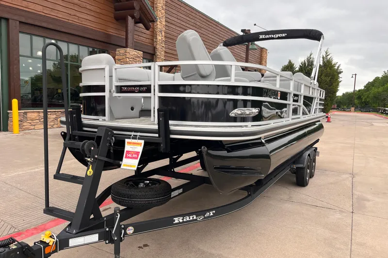 Slide: The Image of 2024 Ranger Reata 220FC pontoon boat on trailer outside a building. - 2