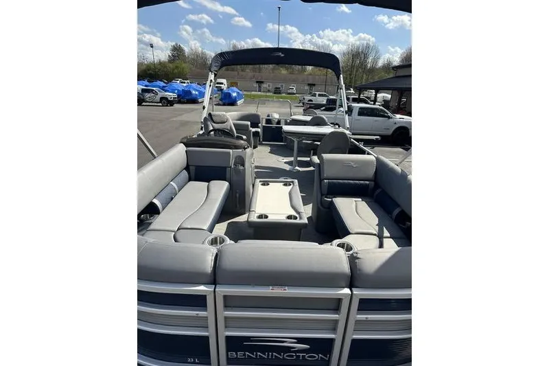 Slide: The Image of 2022 Bennington LPD pontoon boat with spacious seating and canopy, parked outdoors. - 11