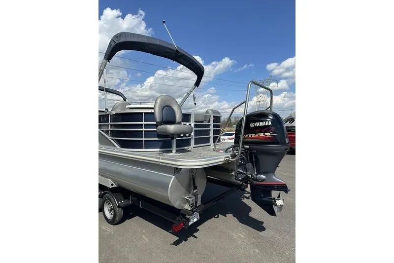 Slide: The Image of 2022 Bennington LPD pontoon boat with Yamaha outboard motor, parked under a clear sky. - 4