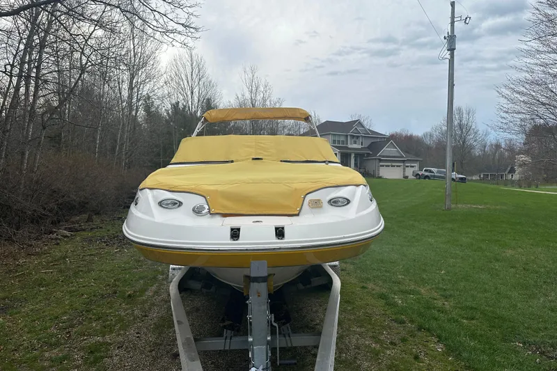 Slide: The Image of 2005 Chaparral Sunesta 216 boat with yellow cover on trailer in suburban setting. - 2