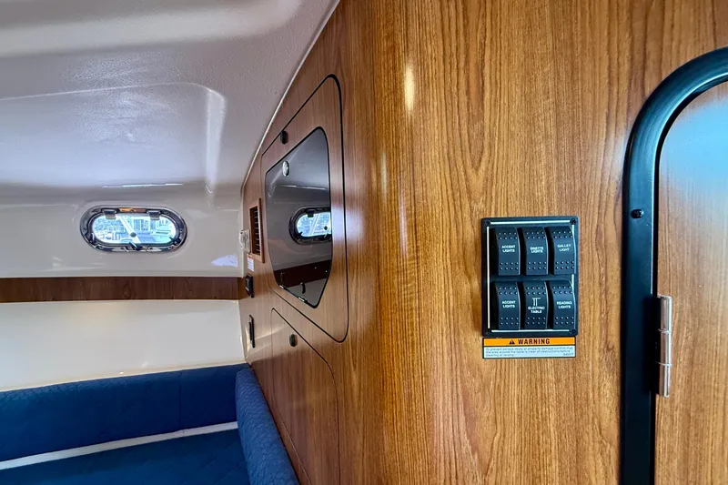 Slide: The Image of Interior of 2012 Pursuit OS 345 Offshore boat with wood paneling and control switches. - 19